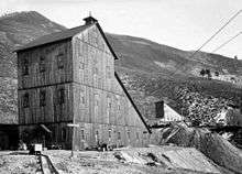 A black and white photograph of two wooden buildings, one closer to the camera than the other