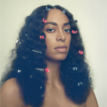 A woman with butterflies on her hair staring at the camera without clothes.