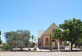 Stone church building with a cross in front