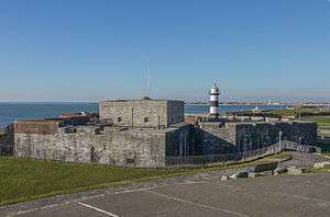 A grey, squat stone castle by the sea shore