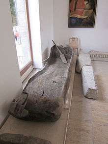 Shallow canoe and paddle next to a window in a museum