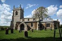 A stone church seen from the south with a battlemented tower to the left and a smaller chancel to the right