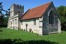 A view of the exterior of the church from the south east - a white-coloured chancel with red tiles, a square perpendicular nave and a stocky tower with large embattlements.