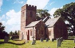 Red stone church with square tower.