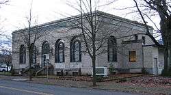 Photograph of the St. Johns Station, a rectangular, single-story building on its own block with tall, arched windows