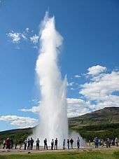 Bystanders watch a nearby geyser erupting.