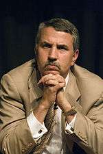 Thomas Friedman in suit clasping hands below chin.