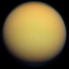 An orange spherical body is half illuminated from the right. The terminator is running from the top to bottom slightly to the left off the center. Both limb and terminator are fuzzy due to light scattering in the atmosphere.