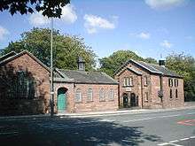 A small chapel seen beyond a school-room, both with round-headed windows