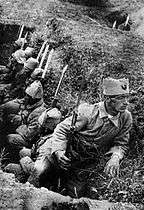 Soldiers in a trench, with one looking in a different direction