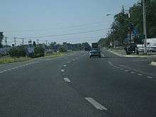 A divided highway curves to the right. In the median are signs indicating the road is entering Delaware.