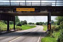 A highway passes underneath a train bridge.