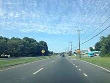 A four-lane divided highway surrounded by businesses and trees