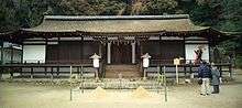 Frontal view of a rather low and wide building with wooden beams and white painted walls.