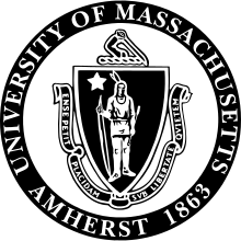 The seal of the University of Massachusetts Amherst, consisting of an American Indian holding a bow at his side in his right hand and an arrow in his left, with a five-pointed star above his right shoulder, enclosed in a shield.  Around the bottom of the shield is a ribbon which reads "Ense Petit Placidam sub Libertate Quietem".  Around the shield and the ribbon is a circle enscribed "University of Massachusetts / Amherst 1863".  The entire seal is in black and white.