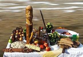 A table on which fruits and some wooden icons are situated.