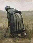 A woman facing away working with a spade