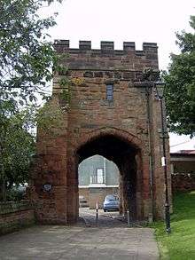 A crenellated tower with a large arched gateway