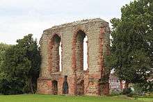 A fragment of a grey sandstone wall containing two large upper windows and two smaller lower ones, each decorated with red sandstone