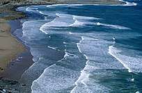 Foam edged waves create a scalloped pattern on a sloping sandy beach