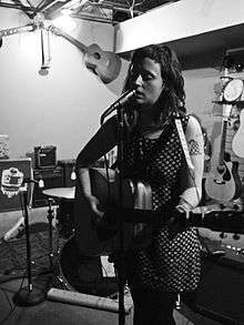 A black-and-white photo of Crutchfield playing guitar and singing into a microphone