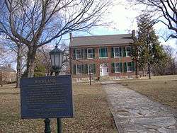 A two-story mansion with a historical marker in the foreground