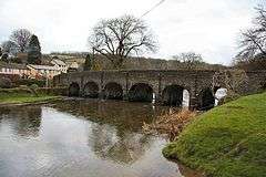 Stone bridge with six arches over water.